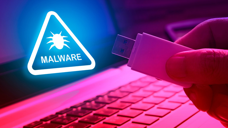A hand holding a thumb drive next to a malware hazard sign
