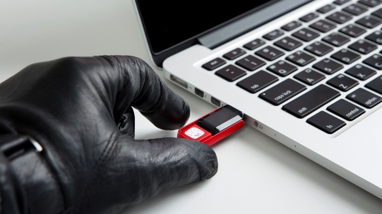 Person holding a USB drive plugged into a laptop