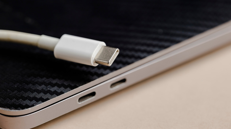 A usb-c cable next to a side profile of a closed laptop showing usb-c ports