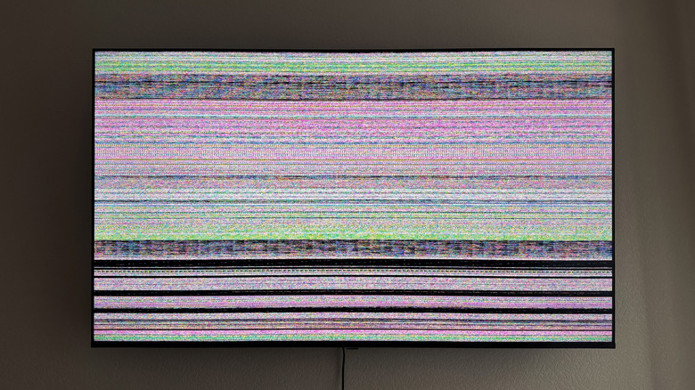 TV hanging on wall with damaged screen with lines all over it