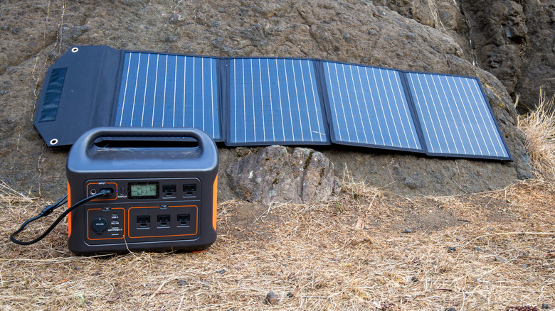 Portable solar panel resting on the ground and hooked up to a solar generator.