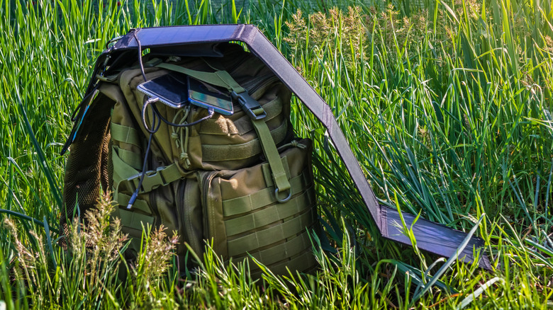 Portable solar panel folded and stretched out on top of a tactical backpack.