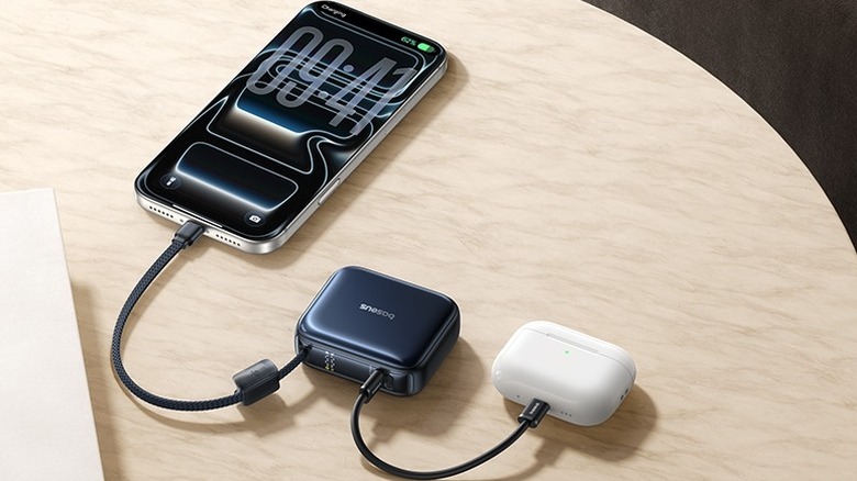 A Baseus PicoGo AC22 Mini charging an iPhone and a pair of AirPods on a wooden table
