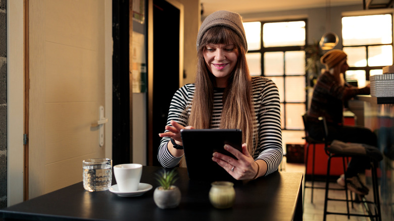 A person reading on a tablet in a coffee shop