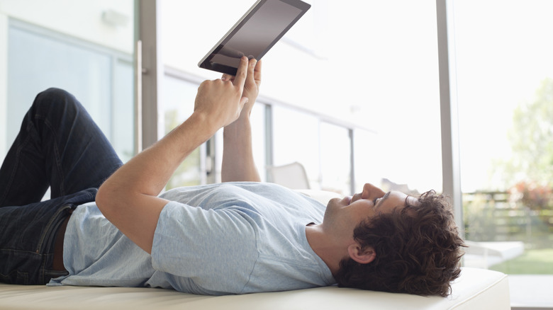 Person reading on a tablet while lying down