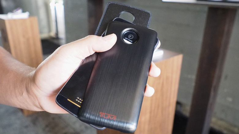 Close-up of a person holding the Moto Z Droid and a couple of Moto Mods