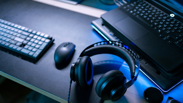 close-up of gaming setup, mouse, keyboard, laptop, and headphones