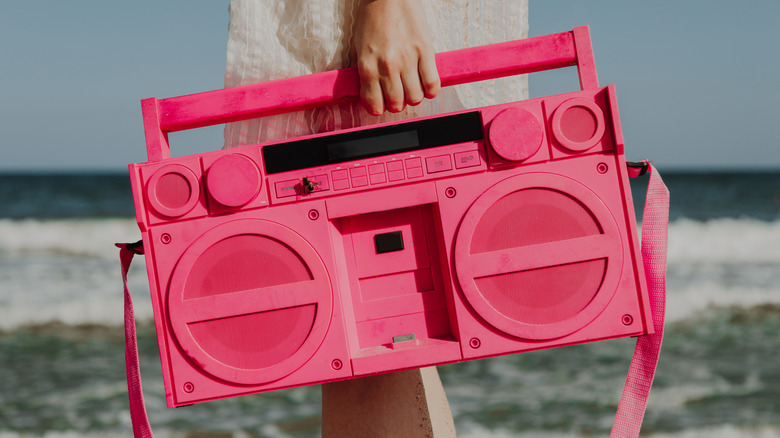 Person holding modern speaker in the style of a vintage boombox