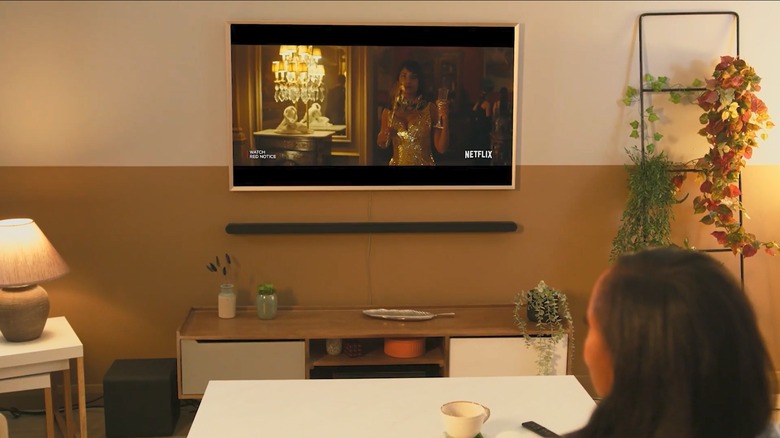 A Samsung TV with a soundbar mounted to the wall beneath it