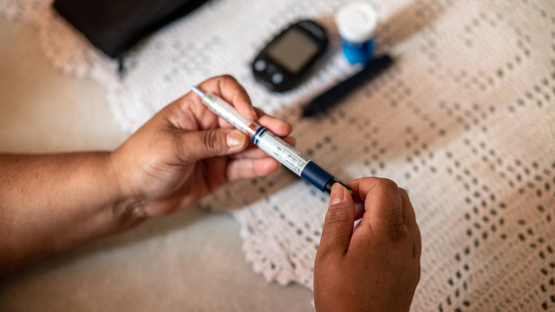 A person preparing an insulin shot, holding the injection in both hands