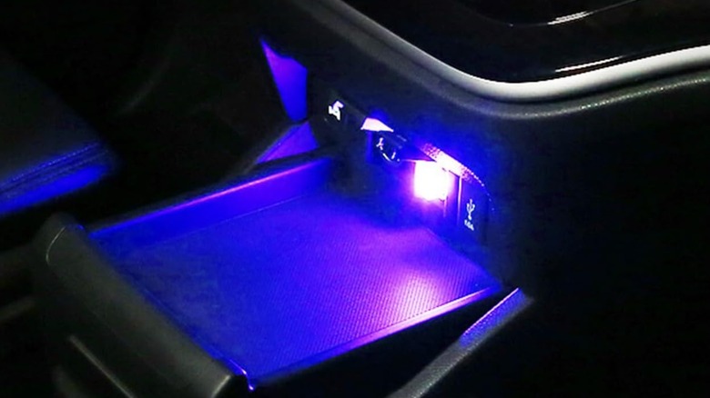 An Amazon promotional photo showcasing one Augeny USB LED interior lamp connected to the USB port of a vehicle's interior, the strong blue light radiates off the interior