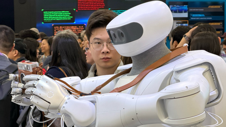 Sharpa's robot taking a photo with a camera to highlight its new hand capabilities