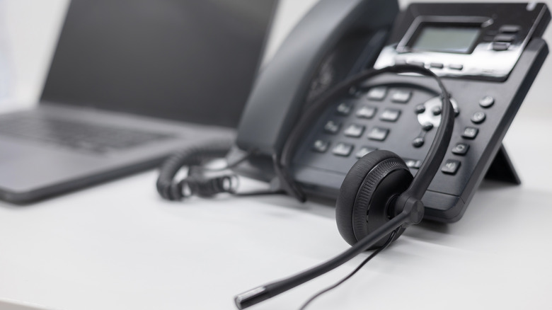 An IP phone and headset beside a laptop