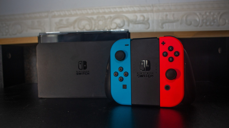 A Nintendo Switch console next to a pair of Joy-Cons in their grip.