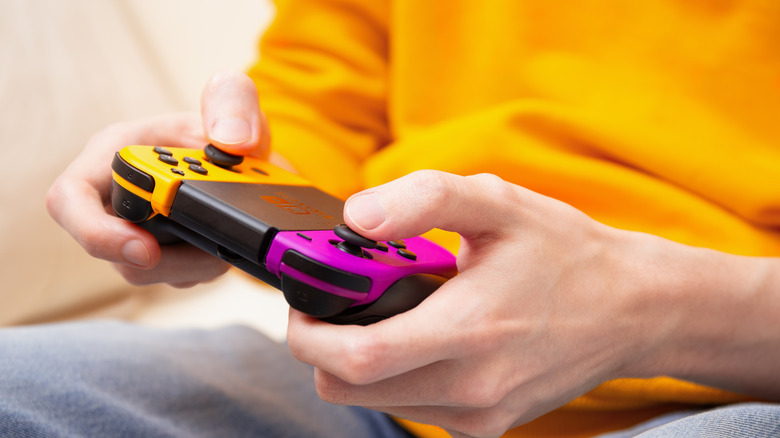 A person playing games with a pair of Nintendo Switch Joy-Cons in a grip.