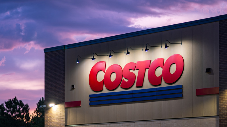 A Costco storefront lit by floodlights set against a dusk sky