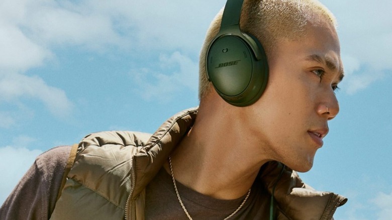 A man wearing a pair of green Bose QuietComfort SC headphones