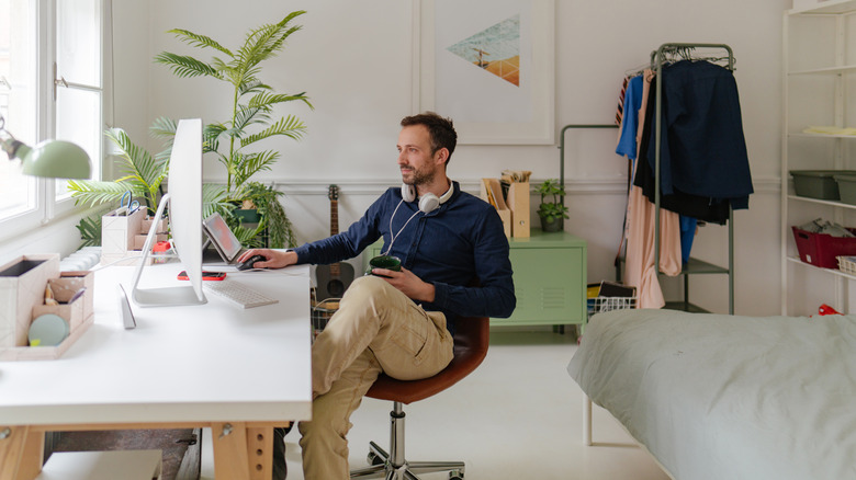 A man sitting working on his computer in a home office setup
