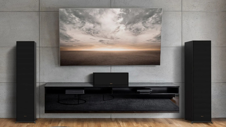 A black Klipsch sound system installed with a smart TV in a modern gray-toned living room lounge