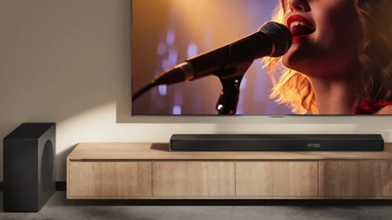 The Hisense AX700 set up below a wall-mounted TV on an entertainment center