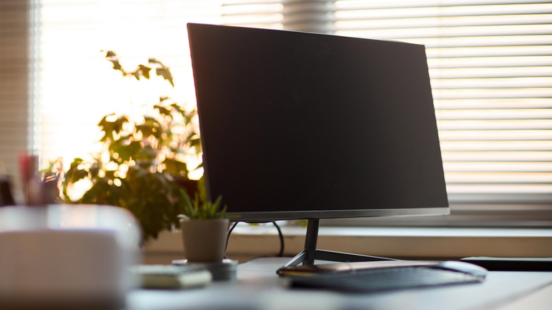A computer monitor on top of an office desk.