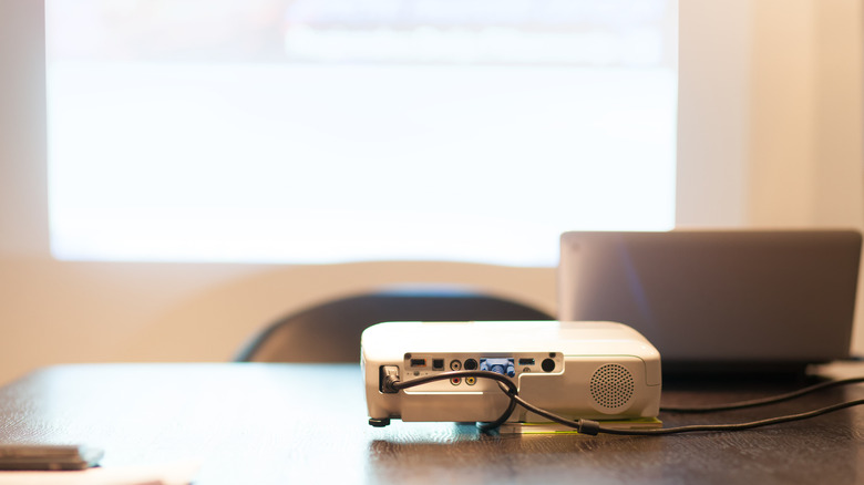 A projector connected to a laptop in a modern office setting.