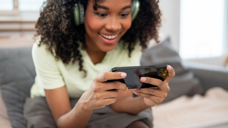 A happy woman playing a mobile game on her mobile phone