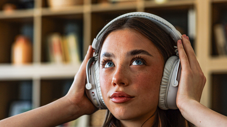 A woman clasping headphones around her head