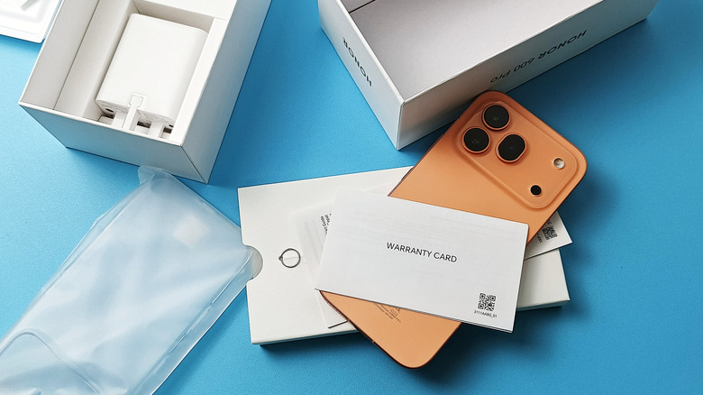 an orange phone that shows a warranty card from the box