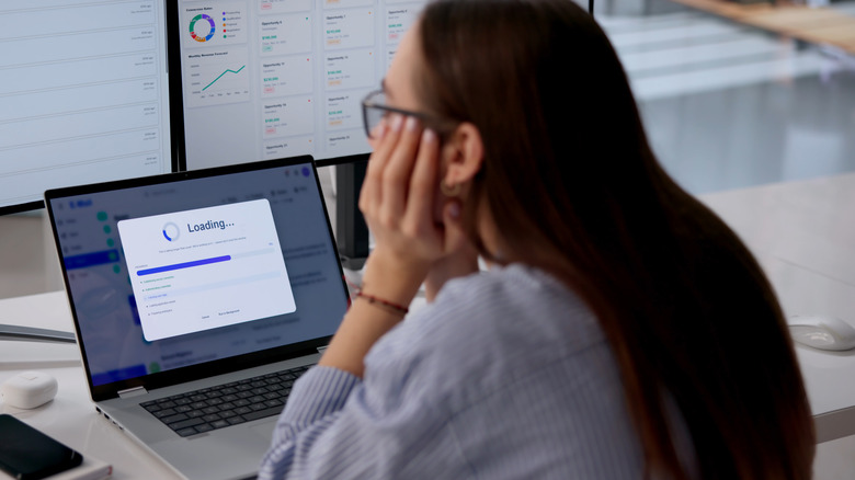 An office worker waiting for an application to load on a laptop