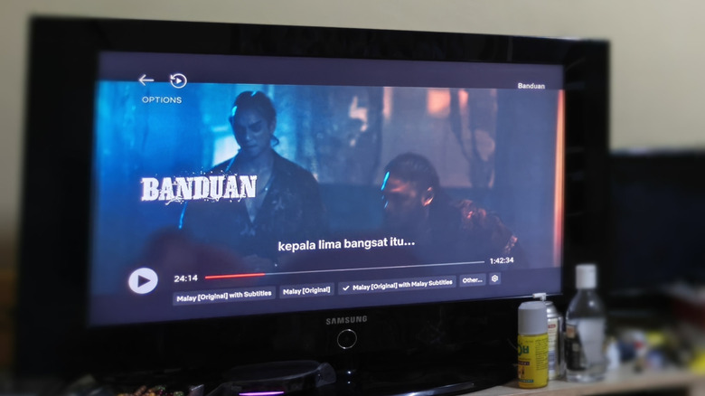 A Samsung TV placed on a table with household items around it