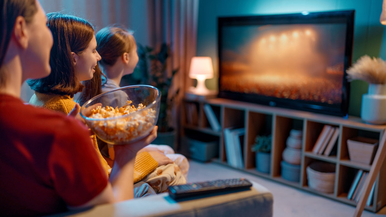 A family watching TV sitting on a sofa