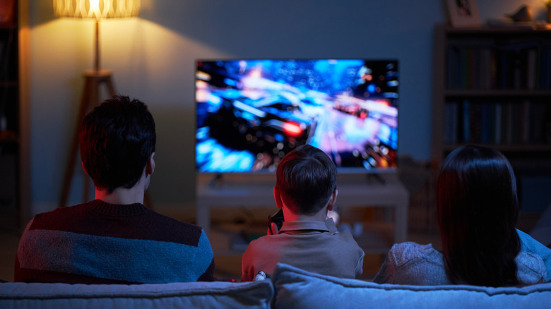 Rear view of a family playing video games on a TV