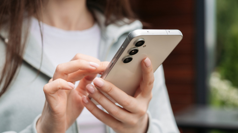 a woman using a Samsung Galaxy S23 FE while outdoors
