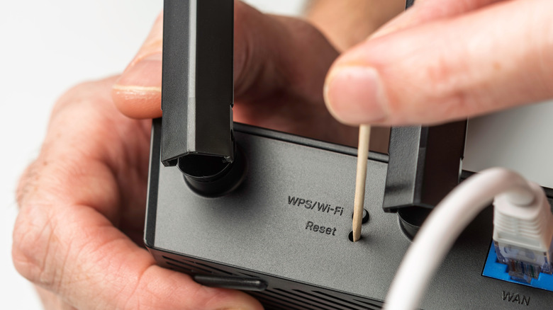 person reseting router with a toothpick