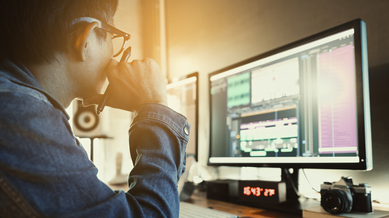 Person editing audio or video at a dual-monitor workstation