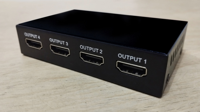 A basic 4x1 HDMI splitter with labeled outputs visible.