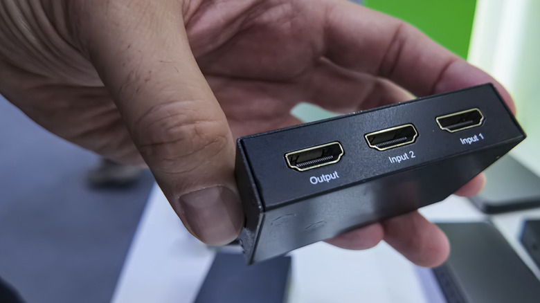 A person holding a small HDMI splitter or switch.