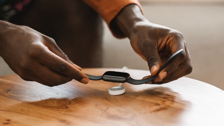 person putting dead smartwatch on charger