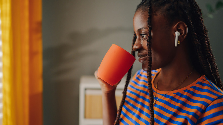 person drinking coffee wearing earbuds