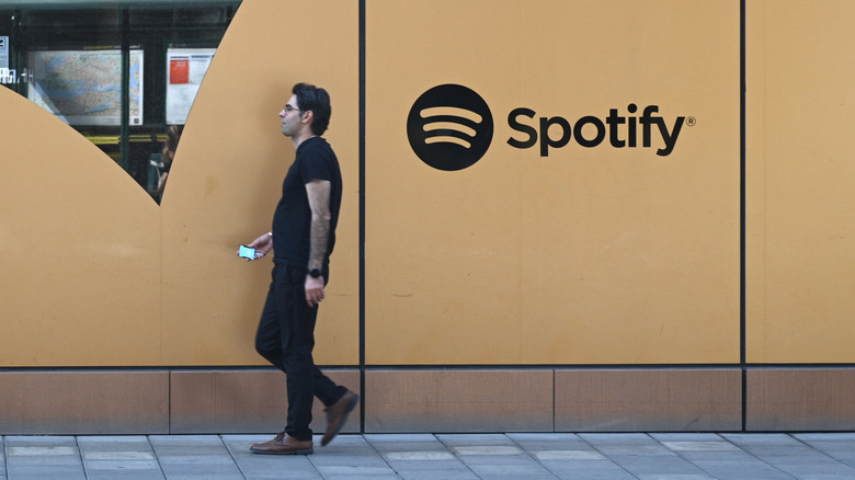 Person walking past Spotify logo on wall of office