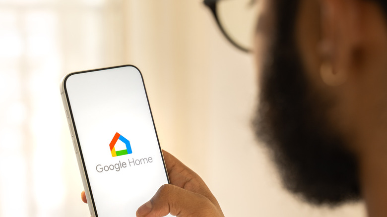 Close-up of man holding phone with Google Home opening up