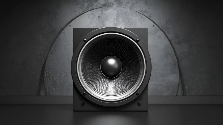 A subwoofer speaker shown in front of a curved wall.