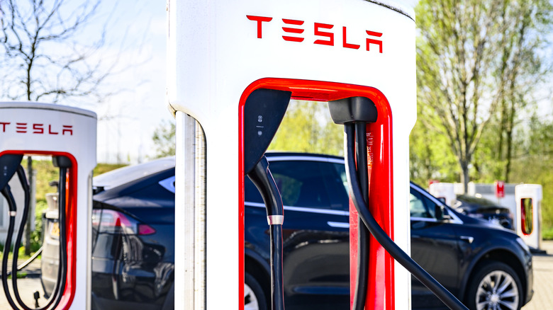 A rack of Tesla charging stations with a vehicle in the background
