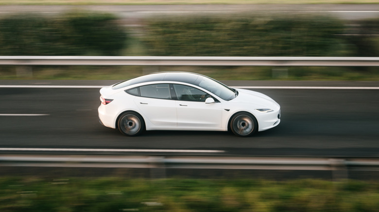 A Tesla Model 3 driving on a highway