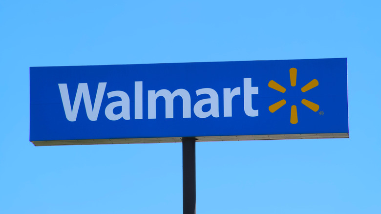 A Walmart sign displaying the company's logo with a clear blue sky behind it