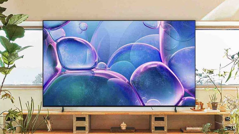 The Samsung 75-inch Class Crystsal UHD 4K Smart TV sitting on top of a TV stand surrounded by various plant life