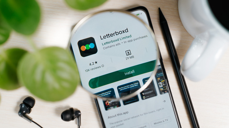 Letterboxd app listing in the Google Play Store on a smartphone screen view through magnifying glass