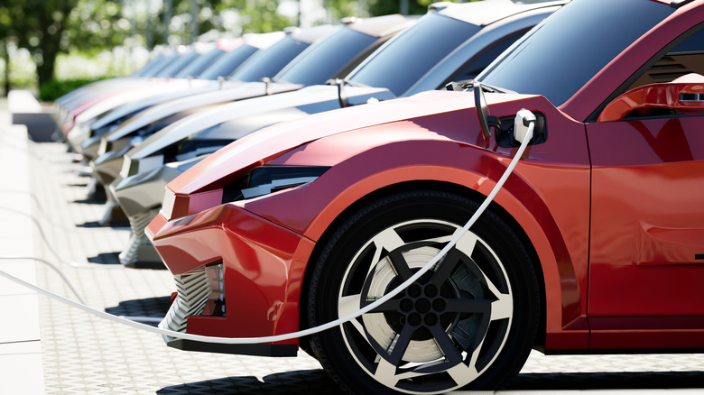 A lineup of electric vehicles with one plugged in.