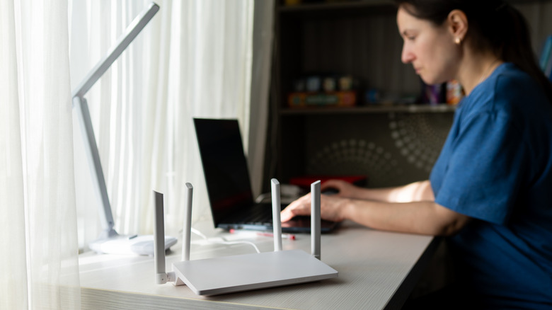 A person working on acomputer next to a Wi-Fi router